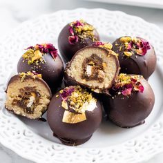 chocolate covered desserts on a white plate with pink flowers and gold sprinkles