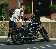 a man standing next to a black motorcycle