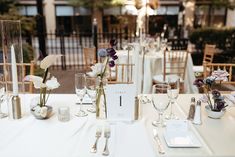 the table is set with silverware and flowers in tall vases on each side