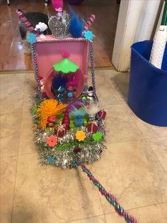 a pink toy carriage filled with lots of colorful items on top of a tiled floor