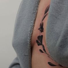 the back of a woman's shoulder with black ink flowers and leaves on it