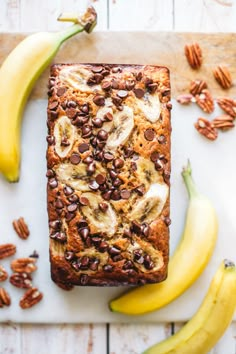 a loaf of banana bread with chocolate chips and pecans around it on a cutting board