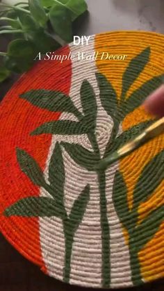 a person is painting a basket with green leaves on the bottom and red, white, and yellow stripes