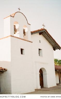 an old white church with two bells on the front and one bell on the back