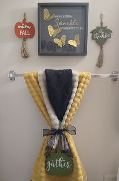 a yellow towel hanging on the wall next to a black and white sign that says gather