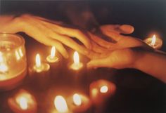 several people are holding hands over some lit candles