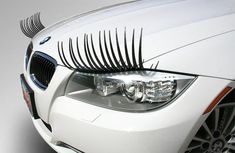 the front end of a white car with eyelashes on it