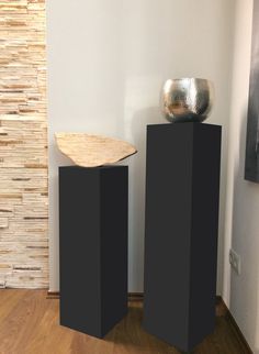 two black pedestals in front of a white wall