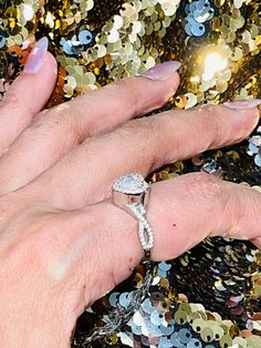 a woman's hand with a diamond ring on top of sequined material