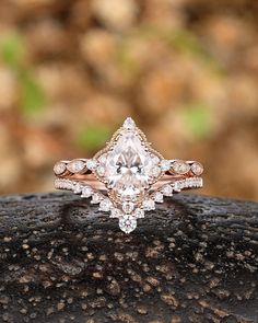 an engagement ring with a pear shaped diamond surrounded by smaller round diamonds on a rock