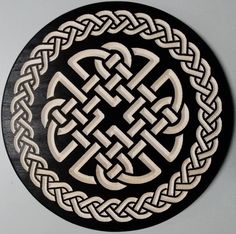 a black and white wall hanging with an intricate knot design on it's side