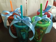 two plastic cups with straws and bows on them sitting on a table next to each other