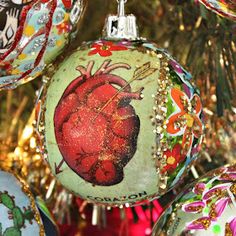 an ornament with a heart on it hanging from a christmas tree in front of other ornaments