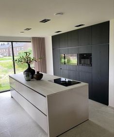 a modern kitchen with black cabinets and white counter tops, along with an island in the middle