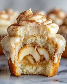 some cupcakes with icing and cinnamon rolls on the top one is cut in half