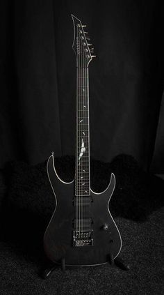 an electric guitar sitting on top of a black carpeted floor in front of a black background