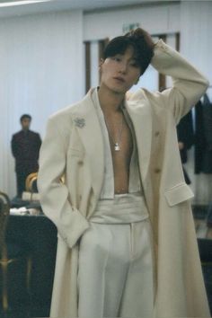 a man in white suit standing next to a table