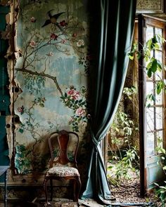 a chair sitting in front of a window next to a wall covered in flowers and birds