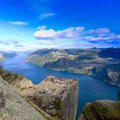 people sitting on the edge of a cliff overlooking a body of water