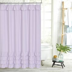 a white bath tub sitting next to a purple shower curtain