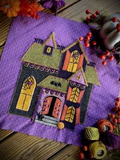 a purple table cloth with a house on it and pumpkins in the foreground