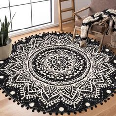 a black and white round rug with pom poms on the floor next to a chair