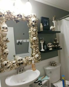 a bathroom with skulls on the wall and a mirror over the toilet, along with a sink