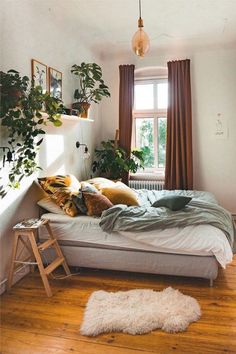 a bedroom with a bed, plants and pictures on the wall in it's corner