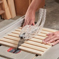 a person using a table saw to cut wooden planks with a large pair of scissors