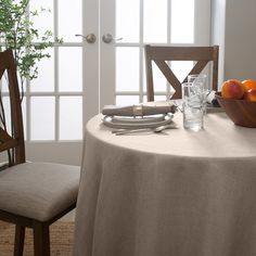 the table is set with silverware and oranges in front of an open door