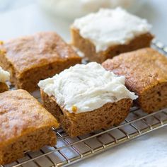 four pieces of cake on a cooling rack with cream cheese frosting in the middle