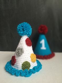 two crocheted party hats sitting next to each other on top of a table