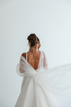 the back of a bride's dress as she holds her veil in front of her face