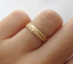 a close up of a person's hand with a gold ring on their finger