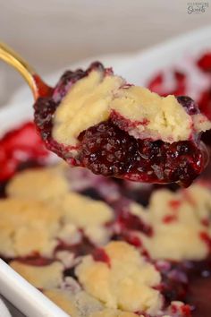 a spoonful of blueberry cobbler is being lifted from a casserole dish