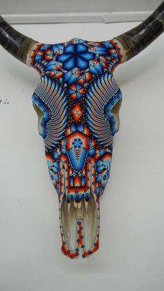 an animal's skull is decorated with blue, red and orange designs