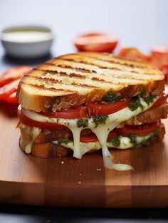 a grilled cheese and tomato sandwich on a cutting board