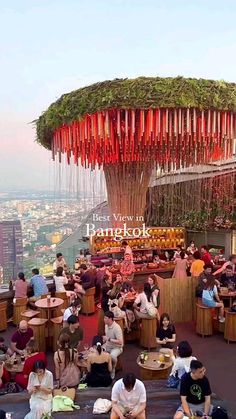 many people are sitting at tables on the top of a building with red ribbons hanging from it's roof