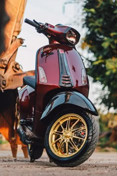 a red scooter with gold rims parked in front of a bull statue