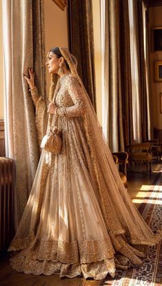 a woman in a bridal gown standing next to a window