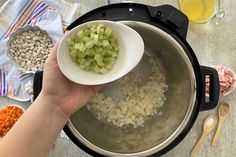 a person holding a bowl with chopped onions and other ingredients in it next to some spoons