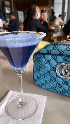 a blue drink sitting next to a purse on top of a table