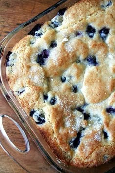 a blueberry cobbler in a glass dish on a wooden table