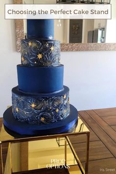 a three tiered blue cake sitting on top of a table next to a mirror