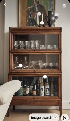 an old wooden shelf with glasses and bottles on it in front of a painting that reads image search