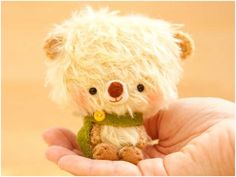 a hand holding a small teddy bear in it's palm