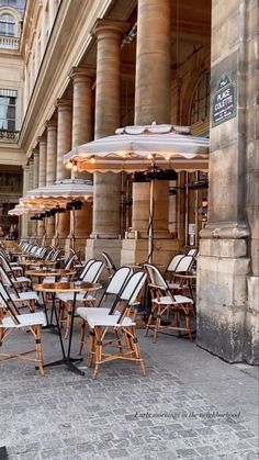 chairs and umbrellas are lined up in front of an old building on the street