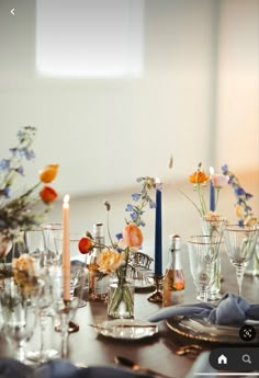 the table is set with candles and flowers in vases, plates and silverware