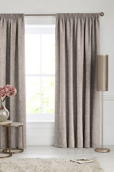 a living room scene with focus on the drapes and flowers in front of the window