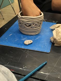 a person sitting at a table with a bowl on top of it and a pencil in front of them